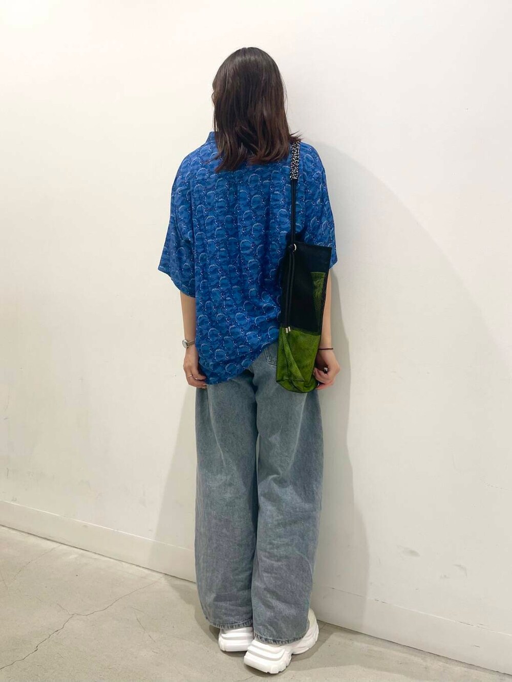 ブルー系のデニムパンツ、ブラック系のショルダーバッグ、ホワイト系のスニーカーを着用したレディースの夏コーディネートの3枚目の写真