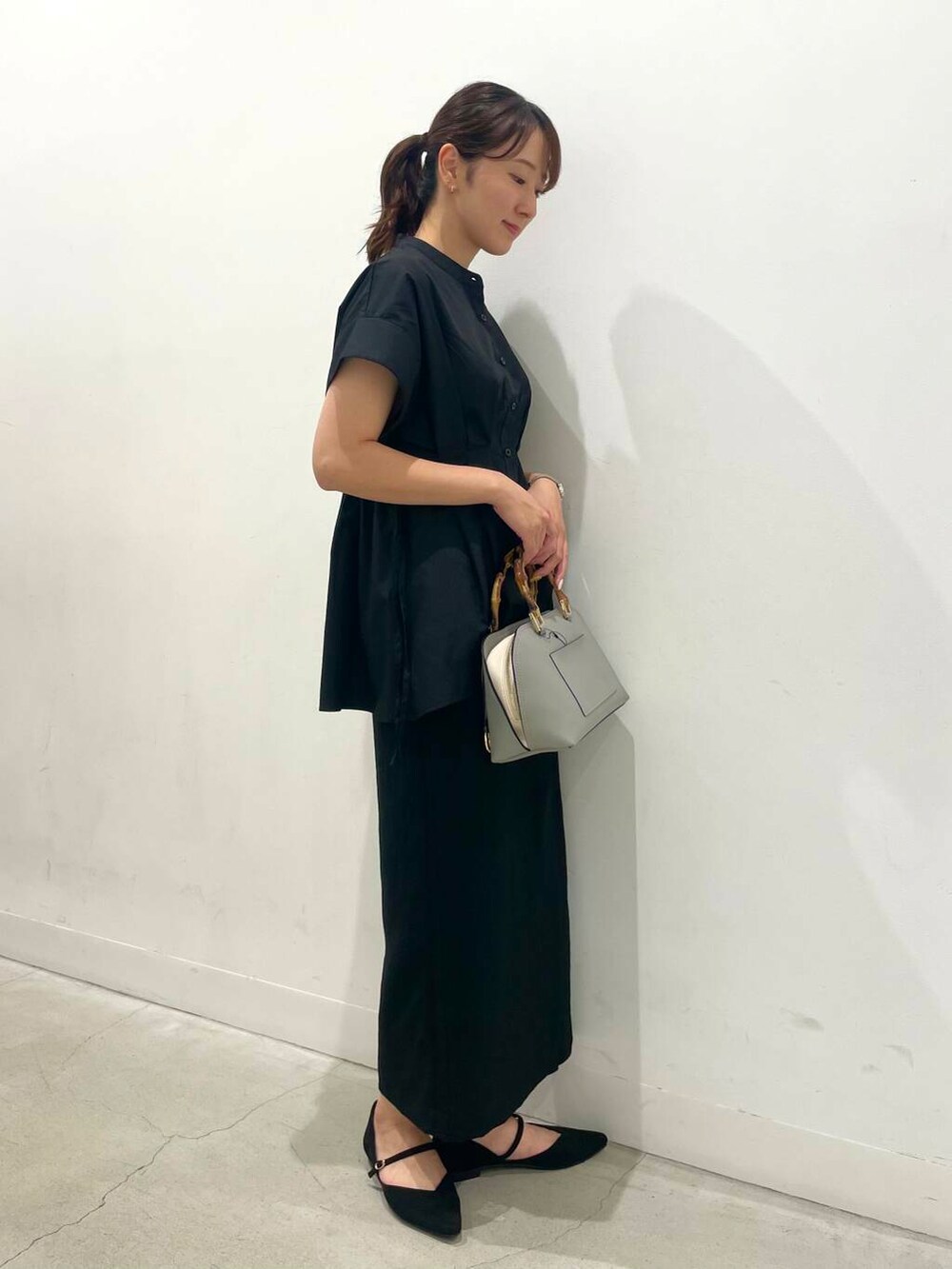 ブラック系のスカート、グレー系のハンドバッグ、ブラック系のパンプスを着用したレディースの夏コーディネートの2枚目の写真