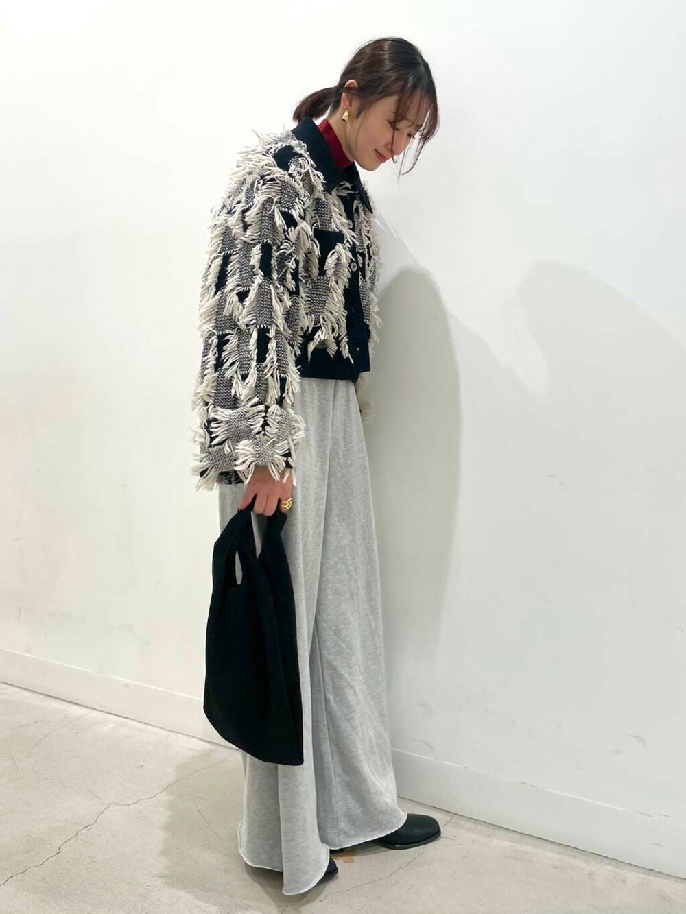 レッド系のニット/セーター、ブラック系のトートバッグ、ブラック系のブーツを着用したレディースの冬コーディネートの2枚目の写真