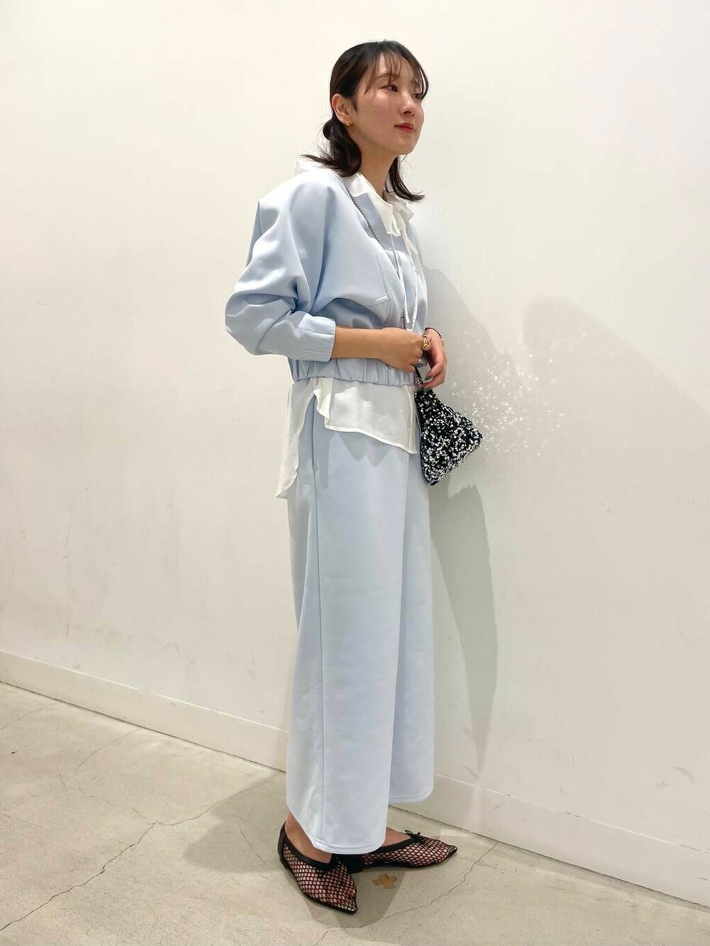 シルバー系のショルダーバッグ、ホワイト系のシャツ/ブラウス、ブラック系のバレエシューズを着用したレディースの春コーディネートの2枚目の写真