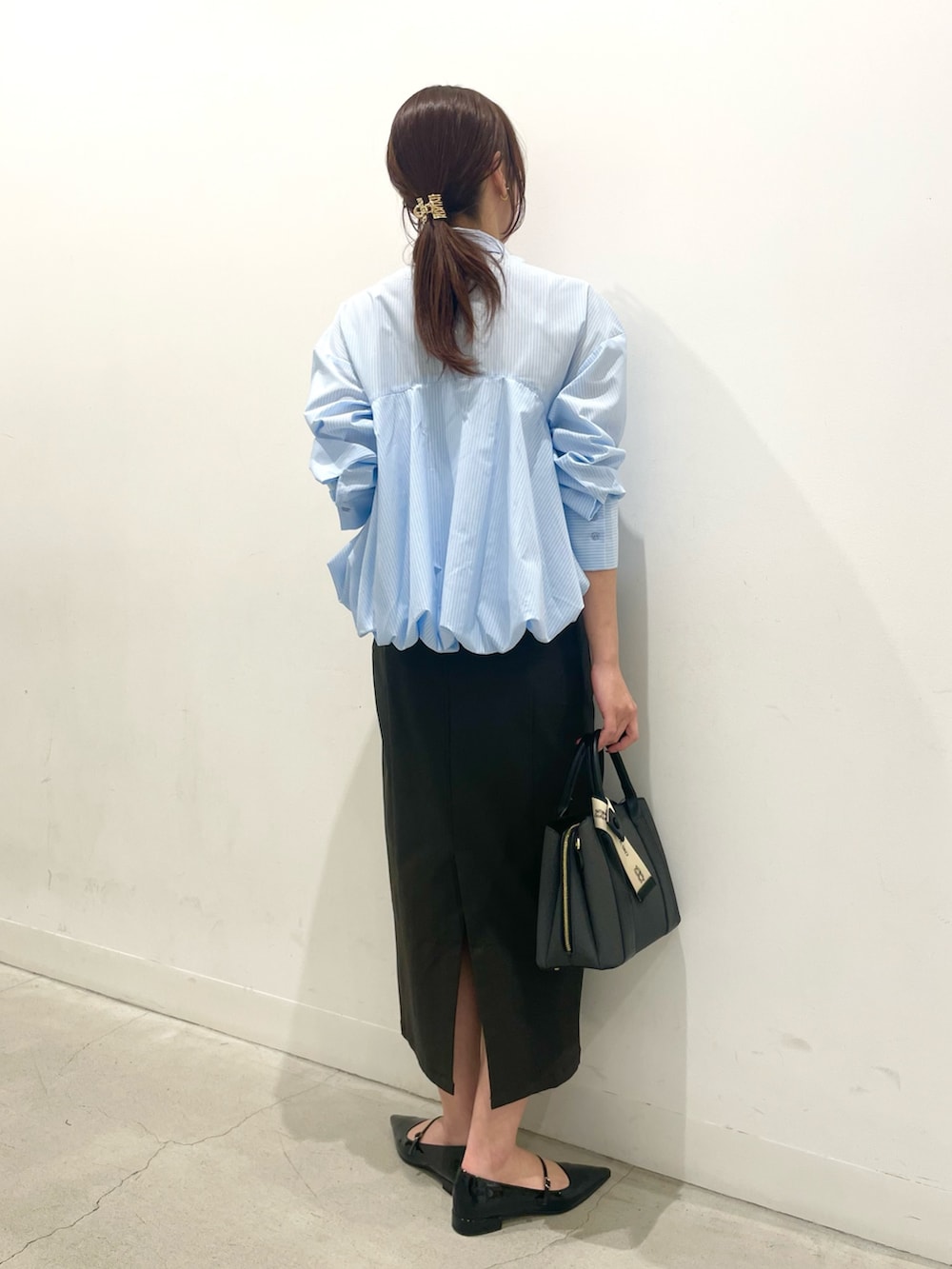 ブラック系のパンプス、ブラック系のハンドバッグ、ブラック系のスカートを着用したレディースの冬コーディネートの3枚目の写真