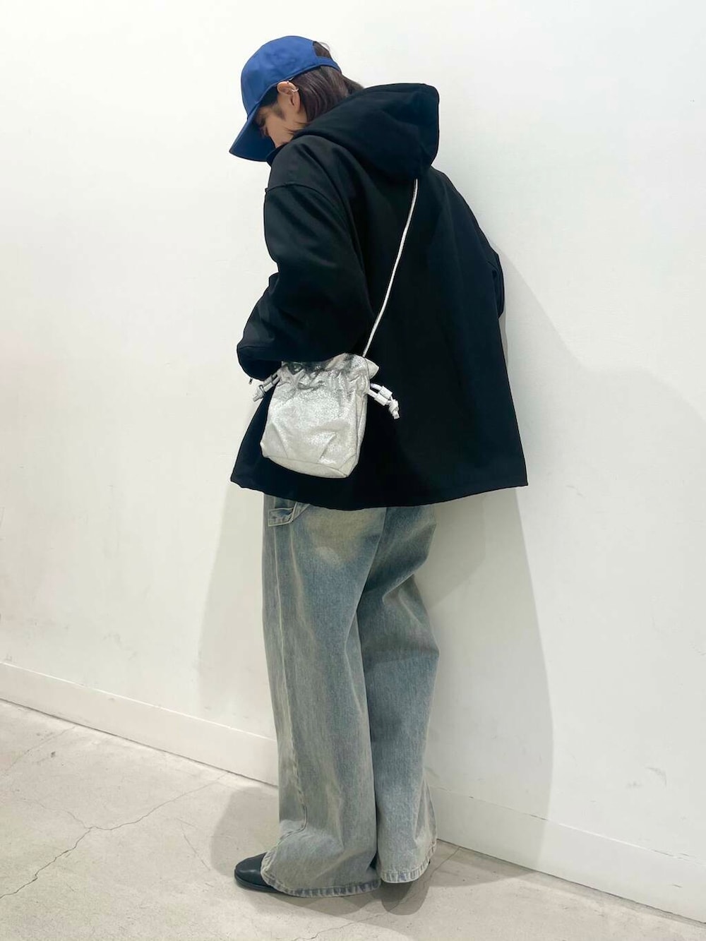 ブラック系のブーツ、ブルー系のデニムパンツ、シルバー系のショルダーバッグを着用したレディースの冬コーディネートの3枚目の写真