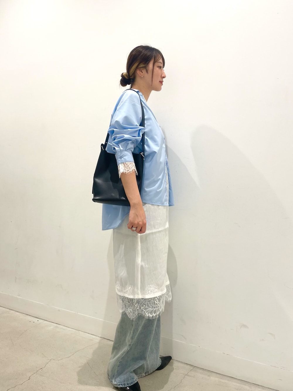 ブラック系のパンプス、ブラック系のショルダーバッグ、ブルー系のデニムパンツを着用したレディースの秋コーディネートの2枚目の写真