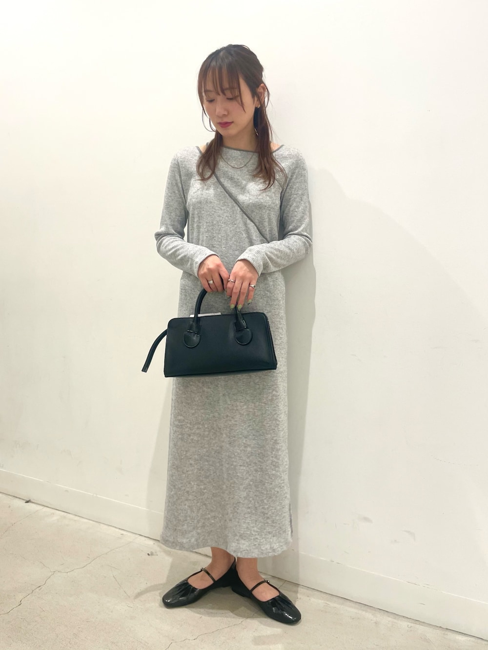 ブラック系のパンプス、ブラック系のボストンバッグ、グレー系のワンピースを着用したレディースの春コーディネートの4枚目の写真