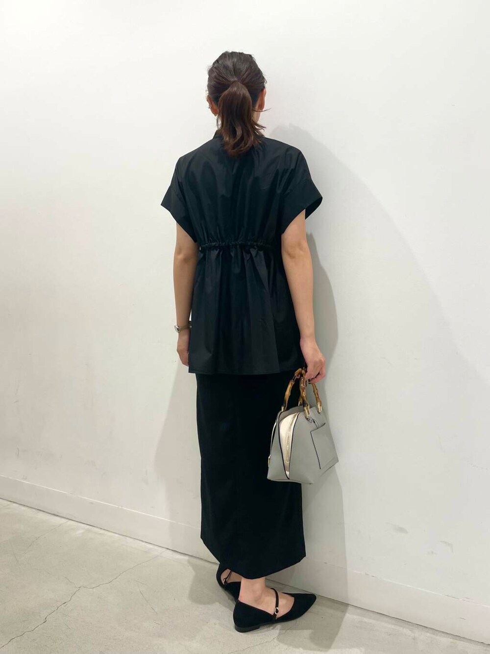 ブラック系のスカート、グレー系のハンドバッグ、ブラック系のパンプスを着用したレディースの夏コーディネートの3枚目の写真