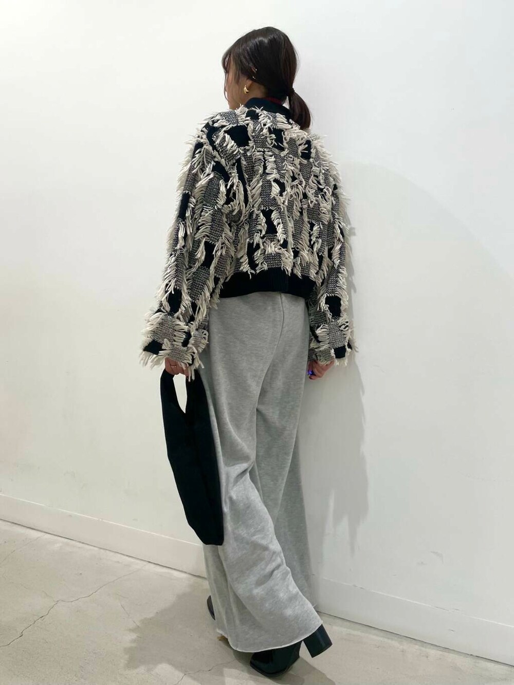 レッド系のニット/セーター、ブラック系のトートバッグ、ブラック系のブーツを着用したレディースの冬コーディネートの3枚目の写真