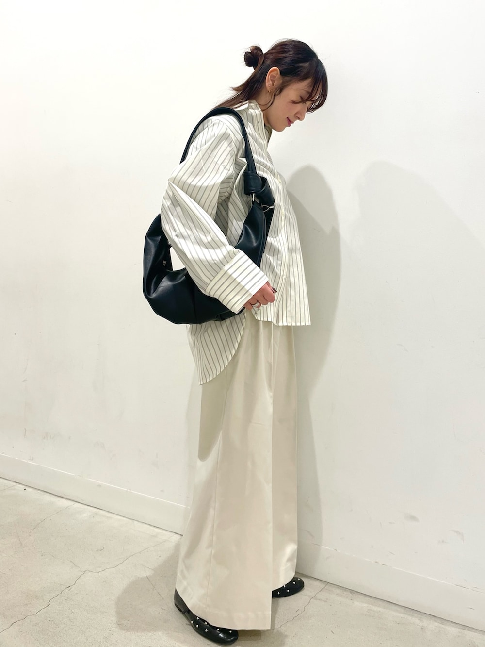 ブラック系のパンプス、ブラック系のショルダーバッグ、ホワイト系のチノパンツを着用したレディースの冬コーディネートの2枚目の写真