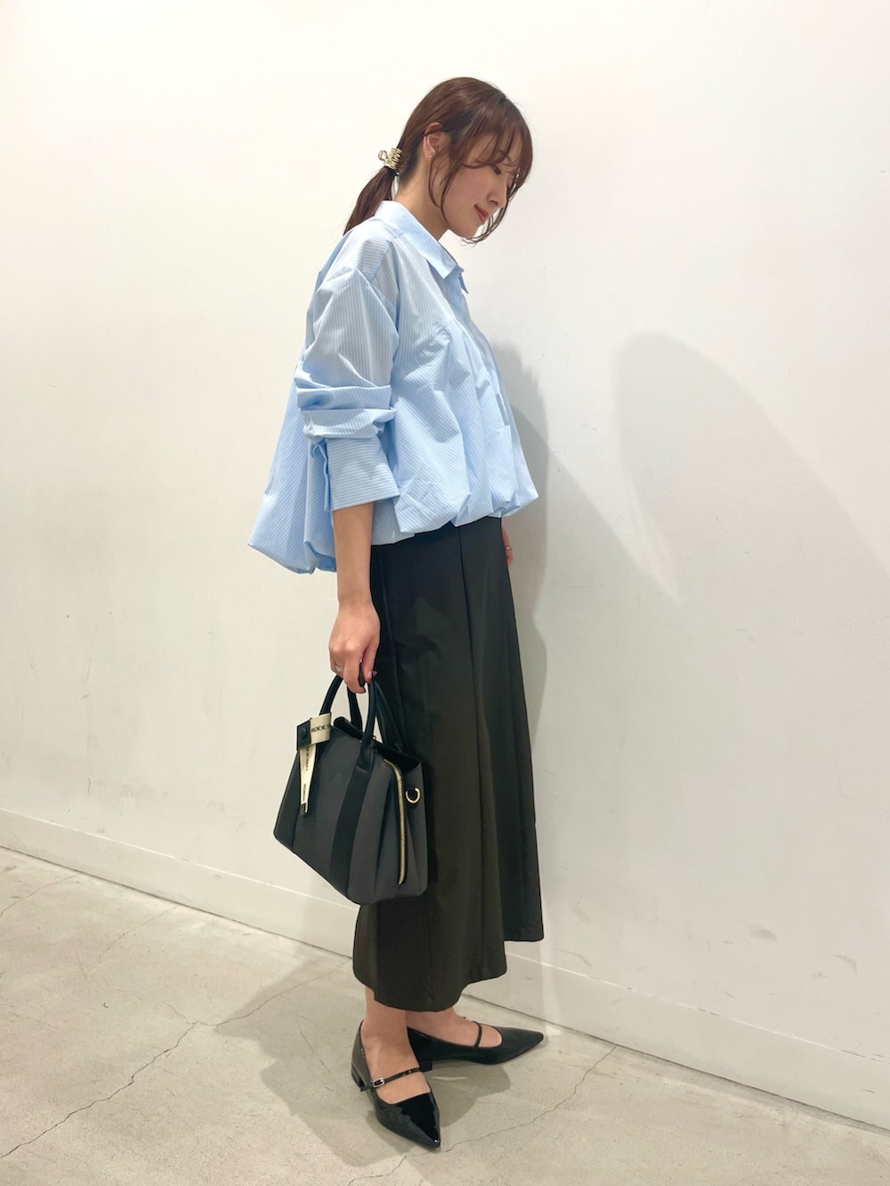 ブラック系のパンプス、ブラック系のハンドバッグ、ブラック系のスカートを着用したレディースの冬コーディネートの2枚目の写真