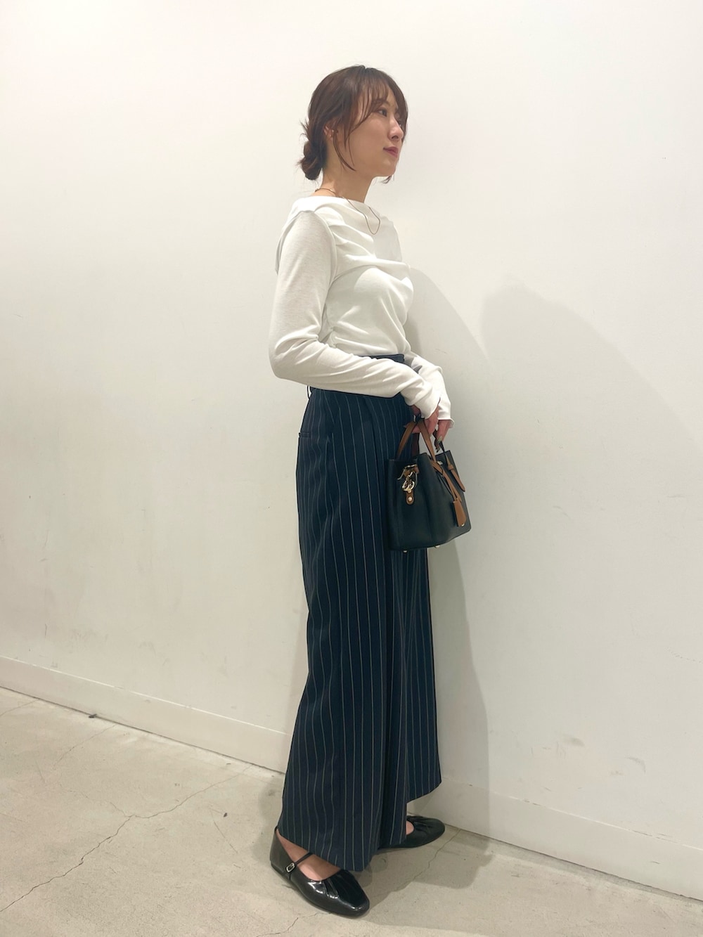 ブラック系のパンプス、ブラック系のハンドバッグ、ブルー系のスカートを着用したレディースの春コーディネートの2枚目の写真