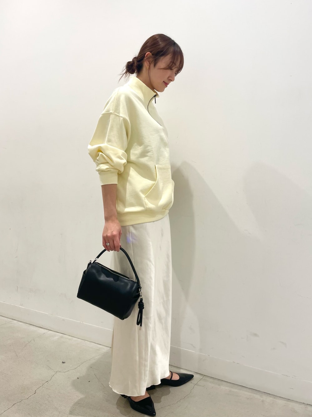 ブラック系のパンプス、ブラック系のハンドバッグ、ホワイト系のスカートを着用したレディースの春コーディネートの2枚目の写真