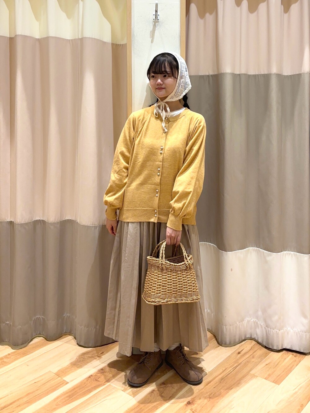 イエロー系のカーディガン/ボレロ、ベージュ系のスカート、ベージュ系のドレスシューズを着用したレディースの秋コーディネートの2枚目の写真