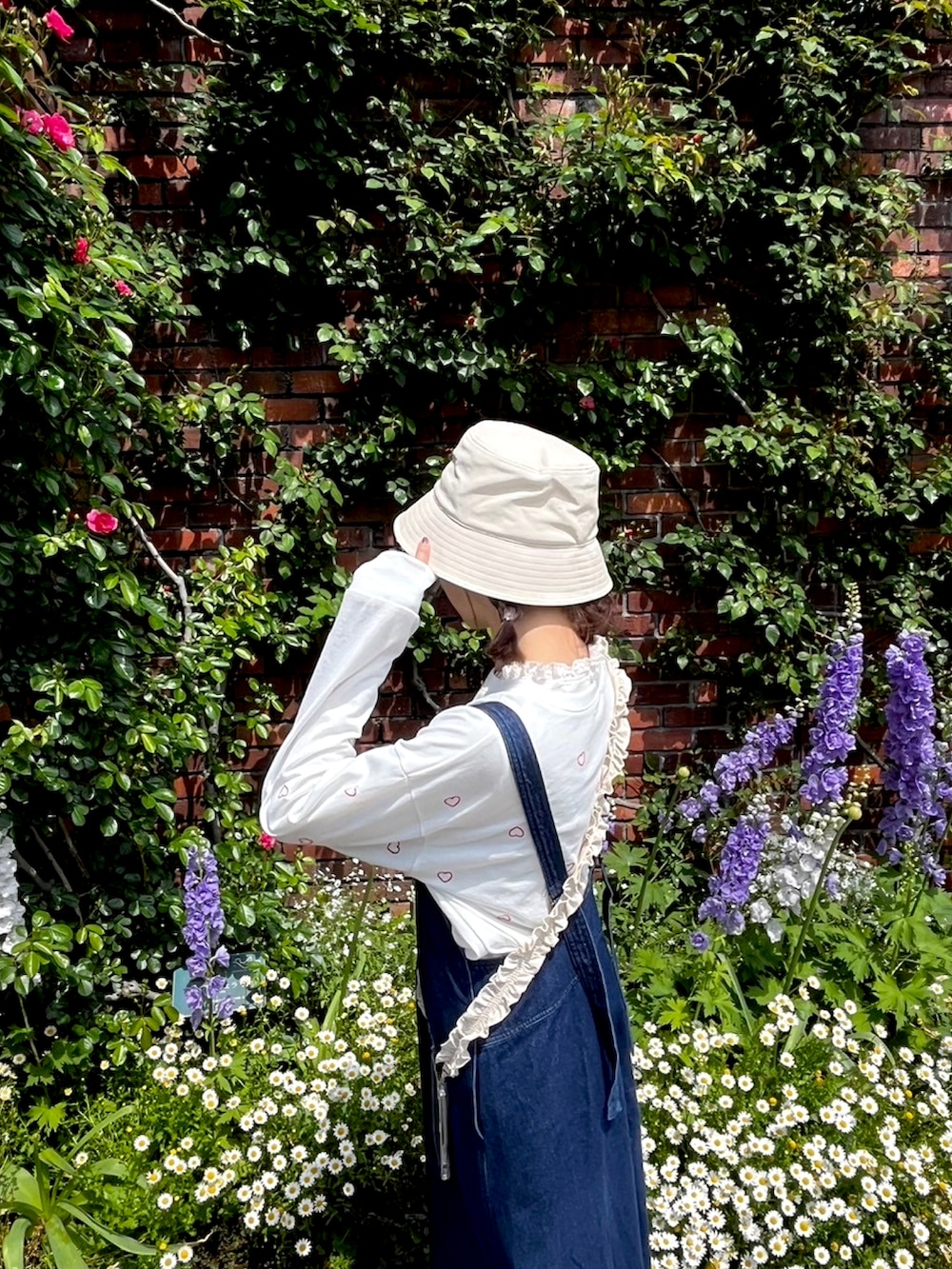 ホワイト系のTシャツ/カットソー、ブラック系のスニーカー、ブルー系のジャンパースカートを着用したレディースの春コーディネートの2枚目の写真