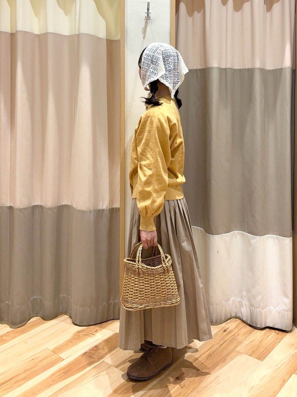 イエロー系のカーディガン/ボレロ、ベージュ系のスカート、ベージュ系のドレスシューズを着用したレディースの秋コーディネートの3枚目の写真