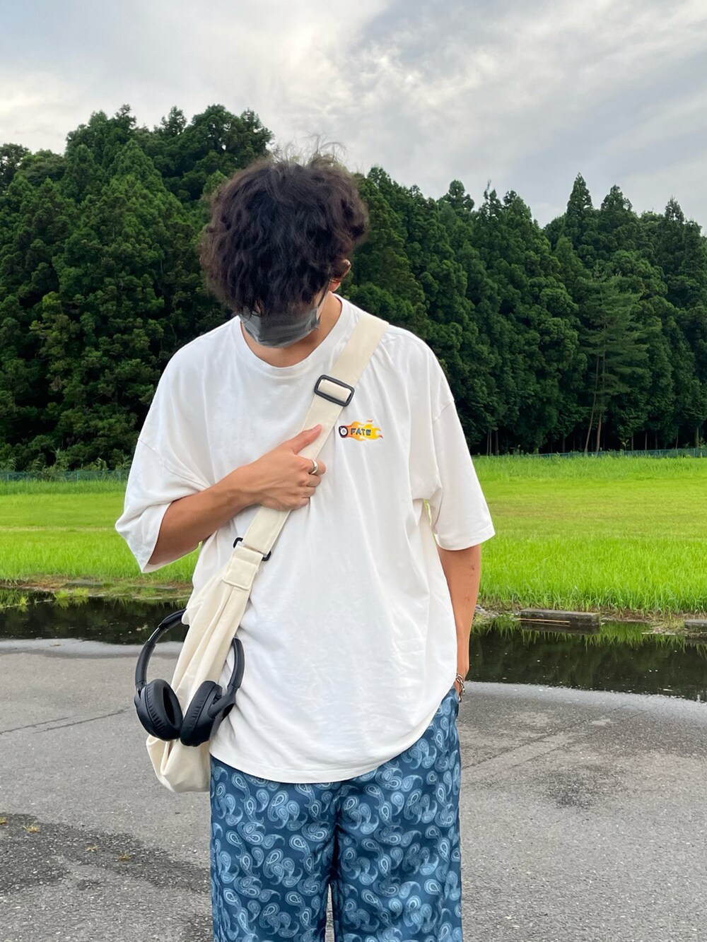 ブルー系のパンツ、ホワイト系のトップス、ベージュ系のバッグを着用したメンズの夏コーディネートの2枚目の写真