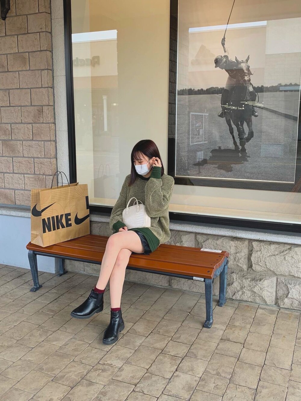 ブラック系のブーツ、ホワイト系のショルダーバッグ、グリーン系のニット/セーターを着用したレディースの秋コーディネートの2枚目の写真