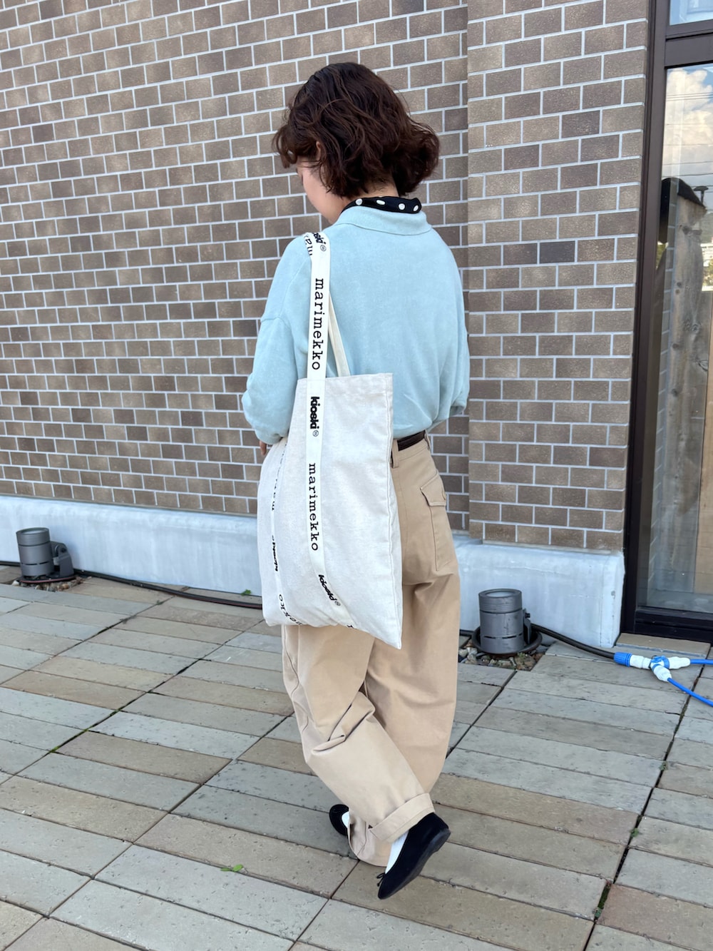 ベージュ系のチノパンツ、ブラック系のバレエシューズ、ホワイト系のトートバッグを着用したレディースの秋コーディネートの2枚目の写真