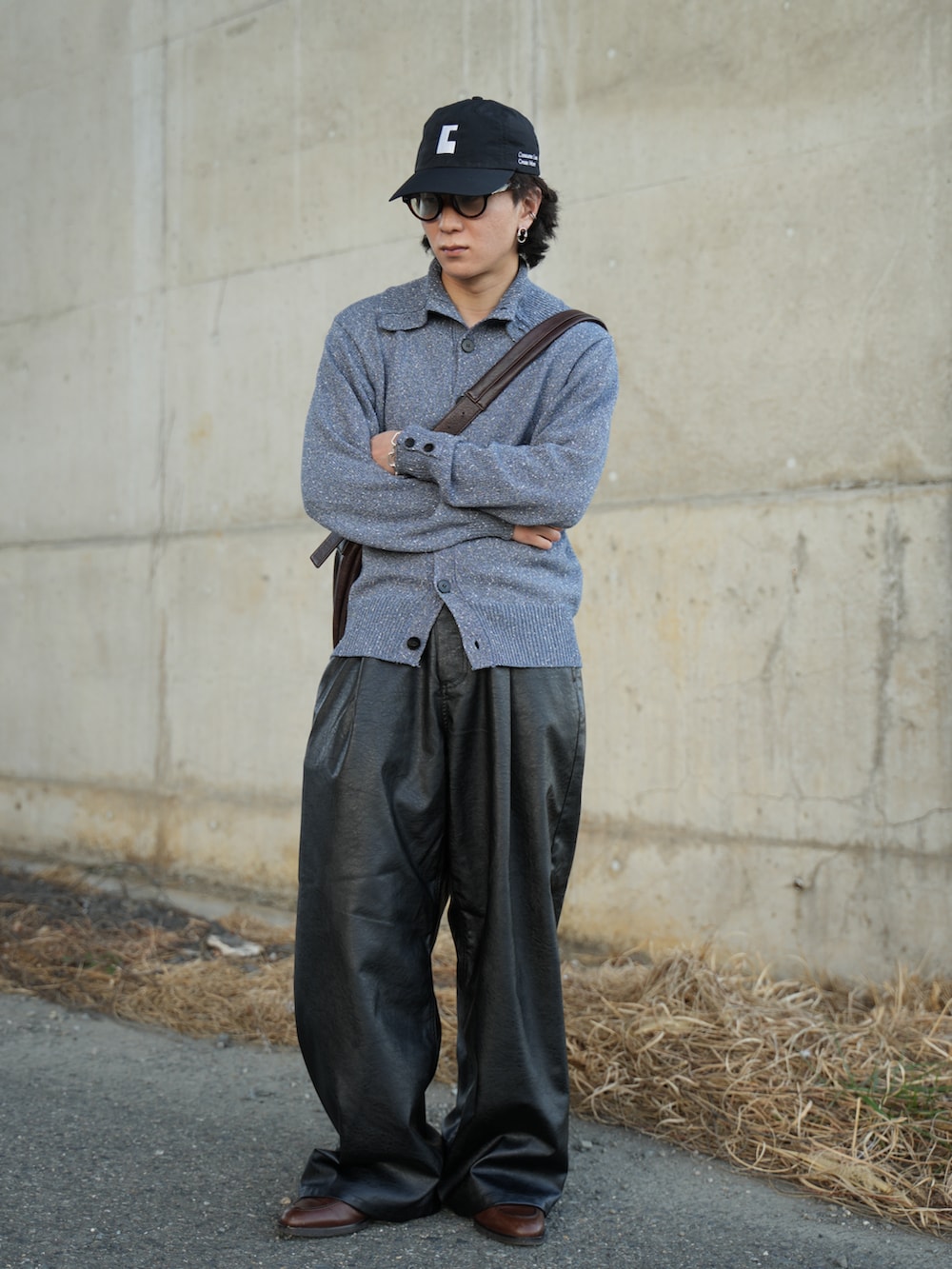 ブルー系のニット/セーター、ブラック系のスラックス、ブラウン系のショルダーバッグを着用したメンズの春コーディネートの4枚目の写真