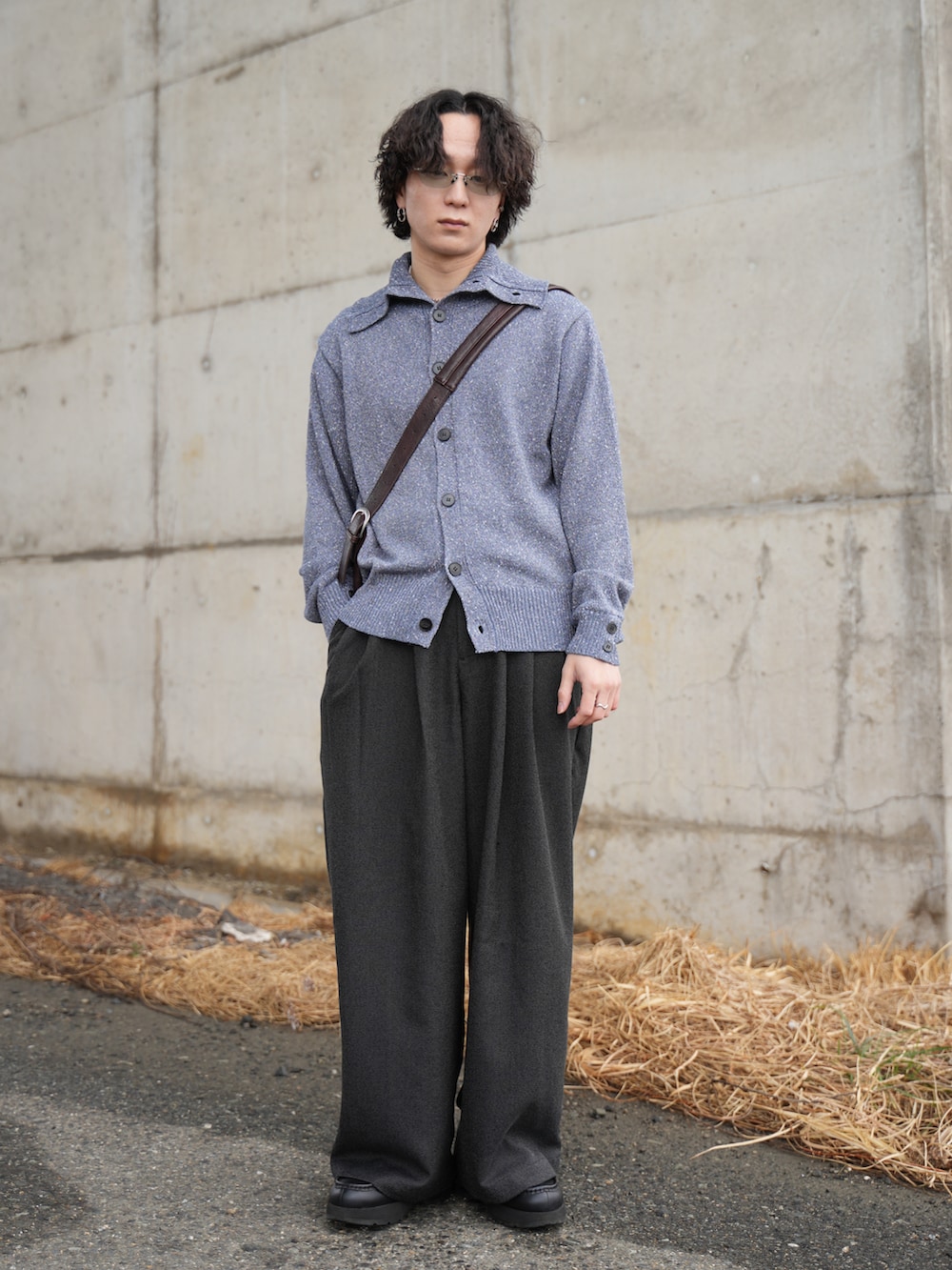 ブルー系のニット/セーター、ブラック系のスラックス、ブラウン系のショルダーバッグを着用したメンズの春コーディネートの4枚目の写真