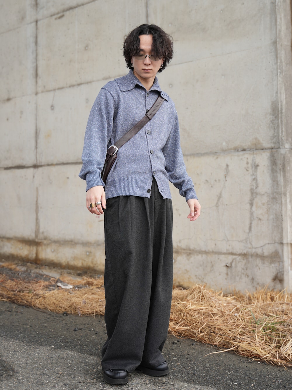 ブルー系のニット/セーター、ブラック系のスラックス、ブラウン系のショルダーバッグを着用したメンズの春コーディネートの5枚目の写真