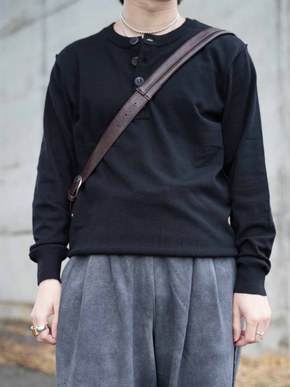 ブラック系のニット/セーター、ブラック系のスウェットパンツ、ブラウン系のショルダーバッグを着用したメンズの春コーディネートの2枚目の写真