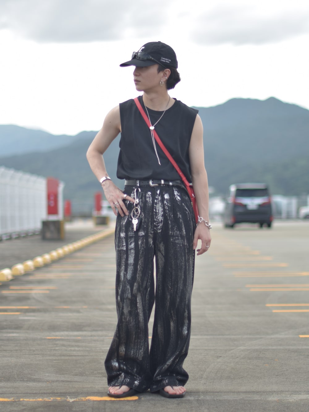 ブラック系のデニムパンツ、レッド系のショルダーバッグ、ブラック系のサンダルを着用したメンズの秋コーディネートの2枚目の写真