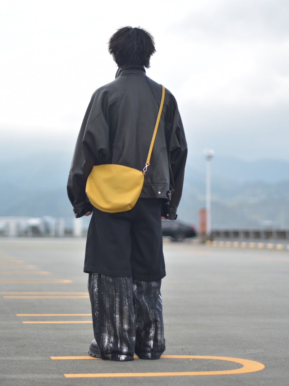 ブラック系のライダースジャケット、イエロー系のショルダーバッグ、ブラック系のその他パンツを着用したメンズの冬コーディネートの5枚目の写真