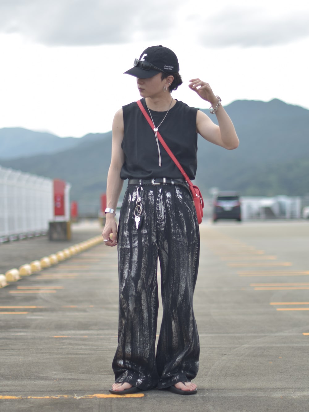 ブラック系のデニムパンツ、レッド系のショルダーバッグ、ブラック系のサンダルを着用したメンズの秋コーディネートの4枚目の写真