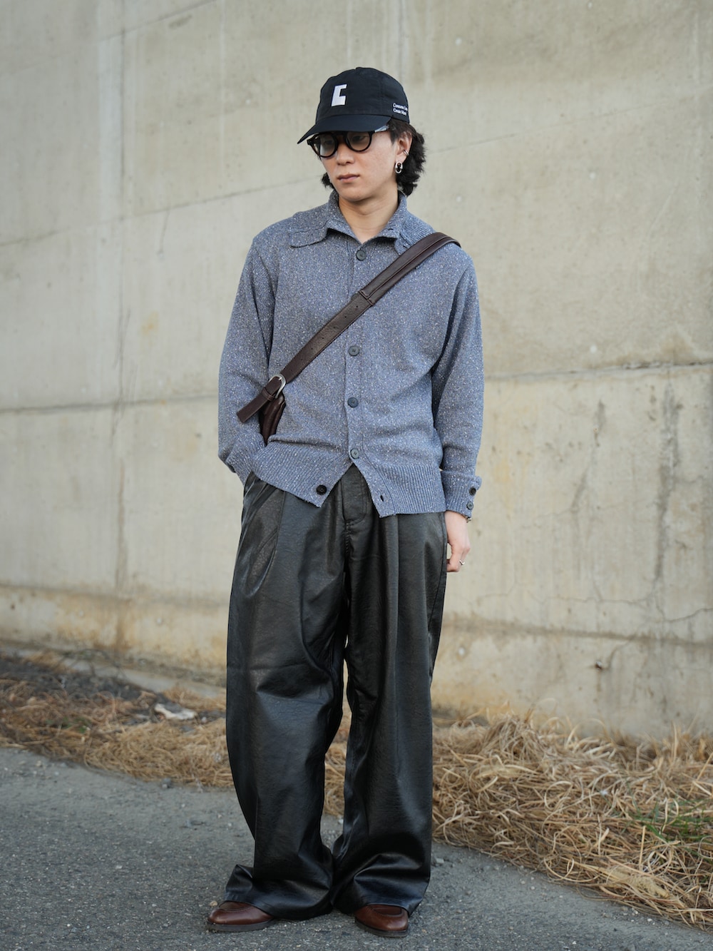 ブルー系のニット/セーター、ブラック系のスラックス、ブラウン系のショルダーバッグを着用したメンズの春コーディネートの5枚目の写真