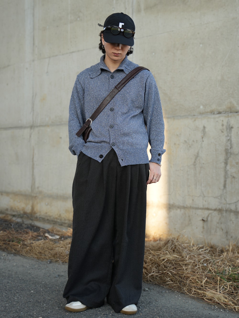 ブルー系のニット/セーター、ブラック系のスラックス、ホワイト系のスニーカーを着用したメンズの春コーディネートの3枚目の写真