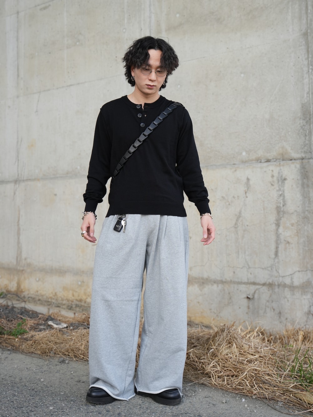 ブラック系のニット/セーター、グレー系のスウェットパンツ、ブラック系のショルダーバッグを着用したメンズの春コーディネートの3枚目の写真