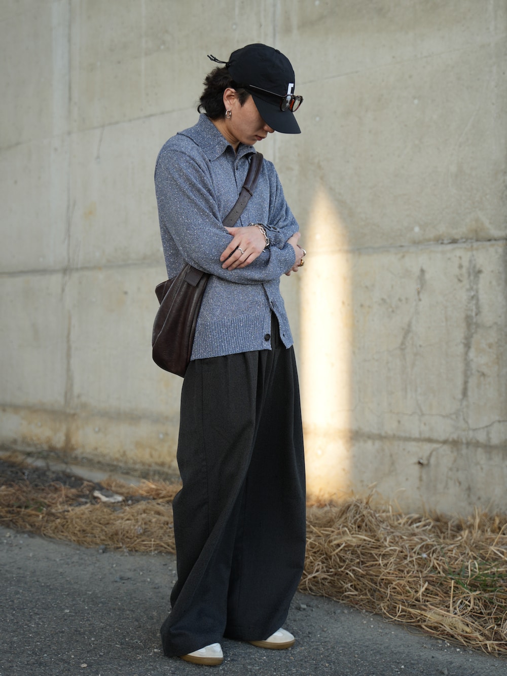 ブルー系のニット/セーター、ブラック系のスラックス、ホワイト系のスニーカーを着用したメンズの春コーディネートの2枚目の写真