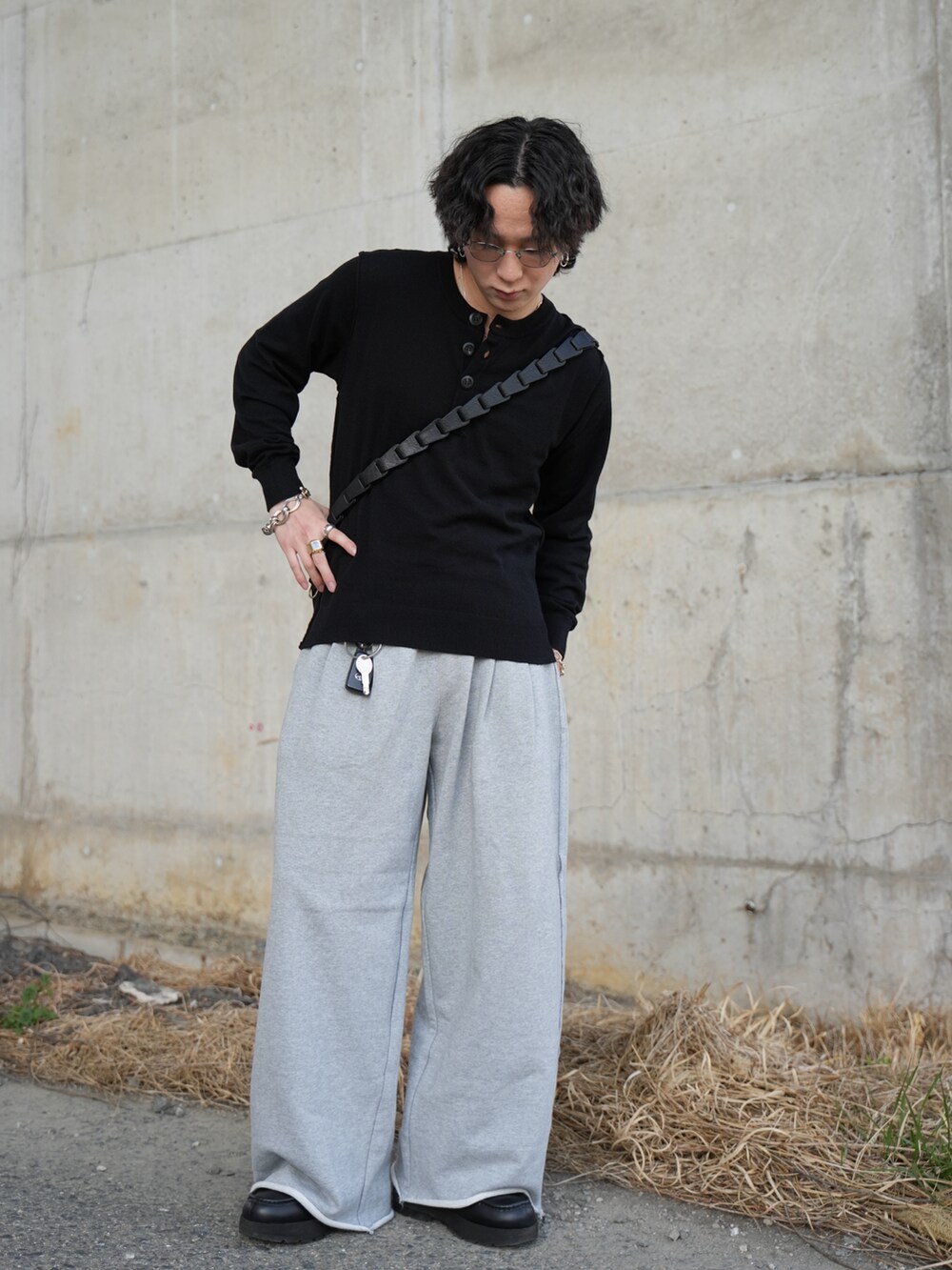 ブラック系のニット/セーター、グレー系のスウェットパンツ、ブラック系のショルダーバッグを着用したメンズの春コーディネートの4枚目の写真