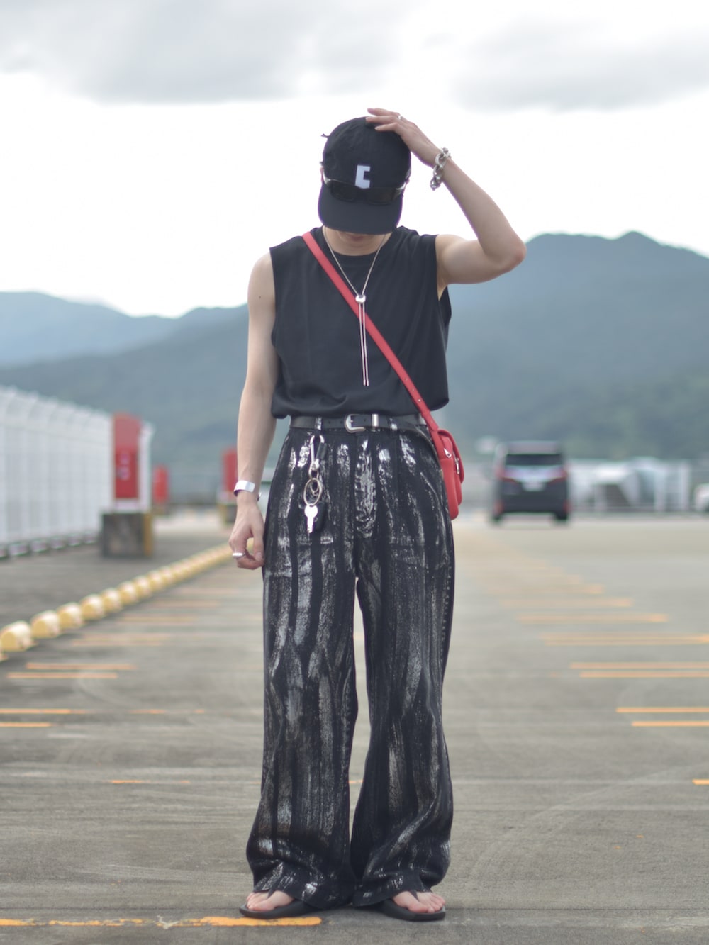 ブラック系のデニムパンツ、レッド系のショルダーバッグ、ブラック系のサンダルを着用したメンズの秋コーディネートの5枚目の写真