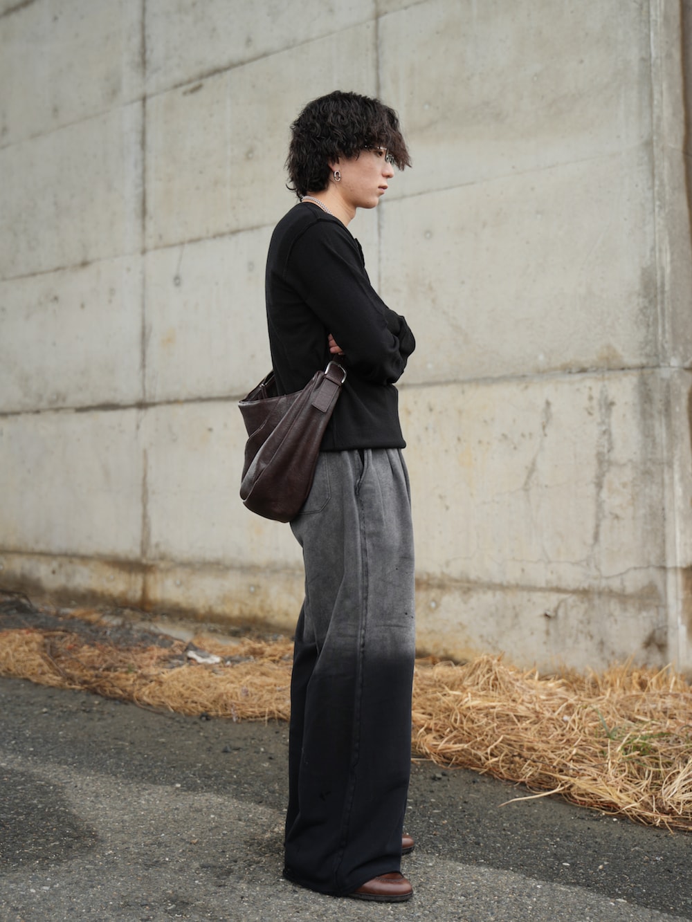 ブラック系のニット/セーター、ブラック系のスウェットパンツ、ブラウン系のショルダーバッグを着用したメンズの春コーディネートの5枚目の写真