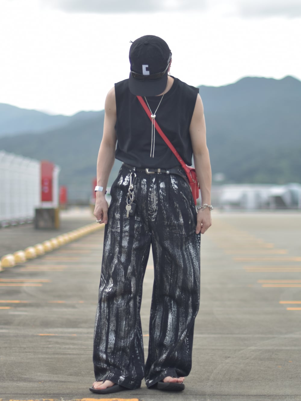 ブラック系のデニムパンツ、レッド系のショルダーバッグ、ブラック系のサンダルを着用したメンズの秋コーディネートの3枚目の写真