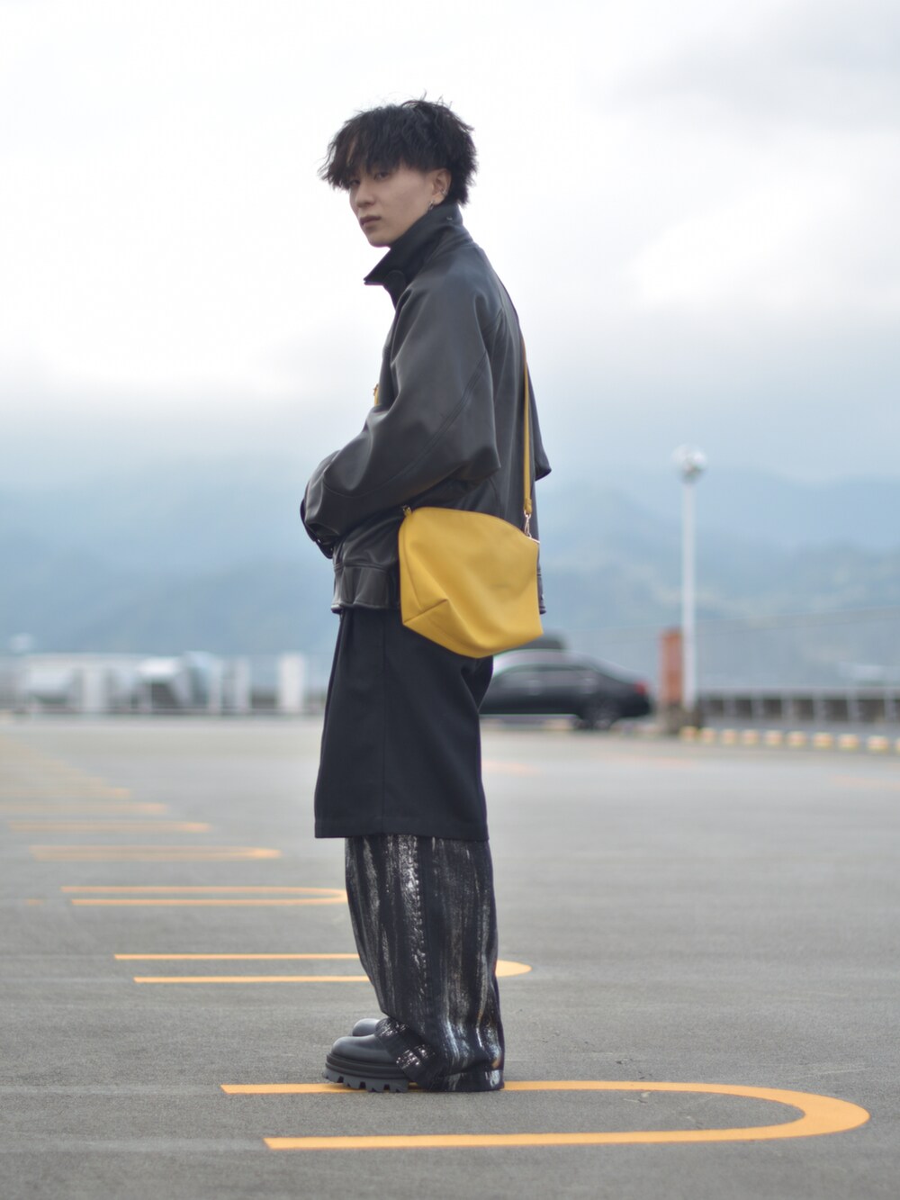 ブラック系のライダースジャケット、イエロー系のショルダーバッグ、ブラック系のその他パンツを着用したメンズの冬コーディネートの4枚目の写真