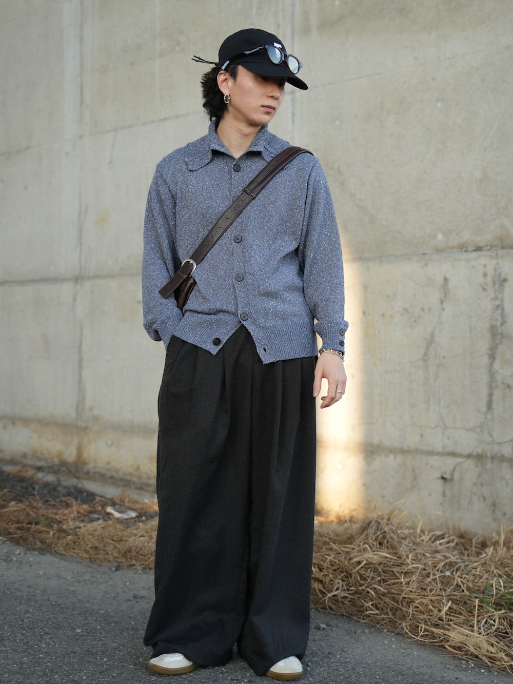 ブルー系のニット/セーター、ブラック系のスラックス、ホワイト系のスニーカーを着用したメンズの春コーディネートの4枚目の写真