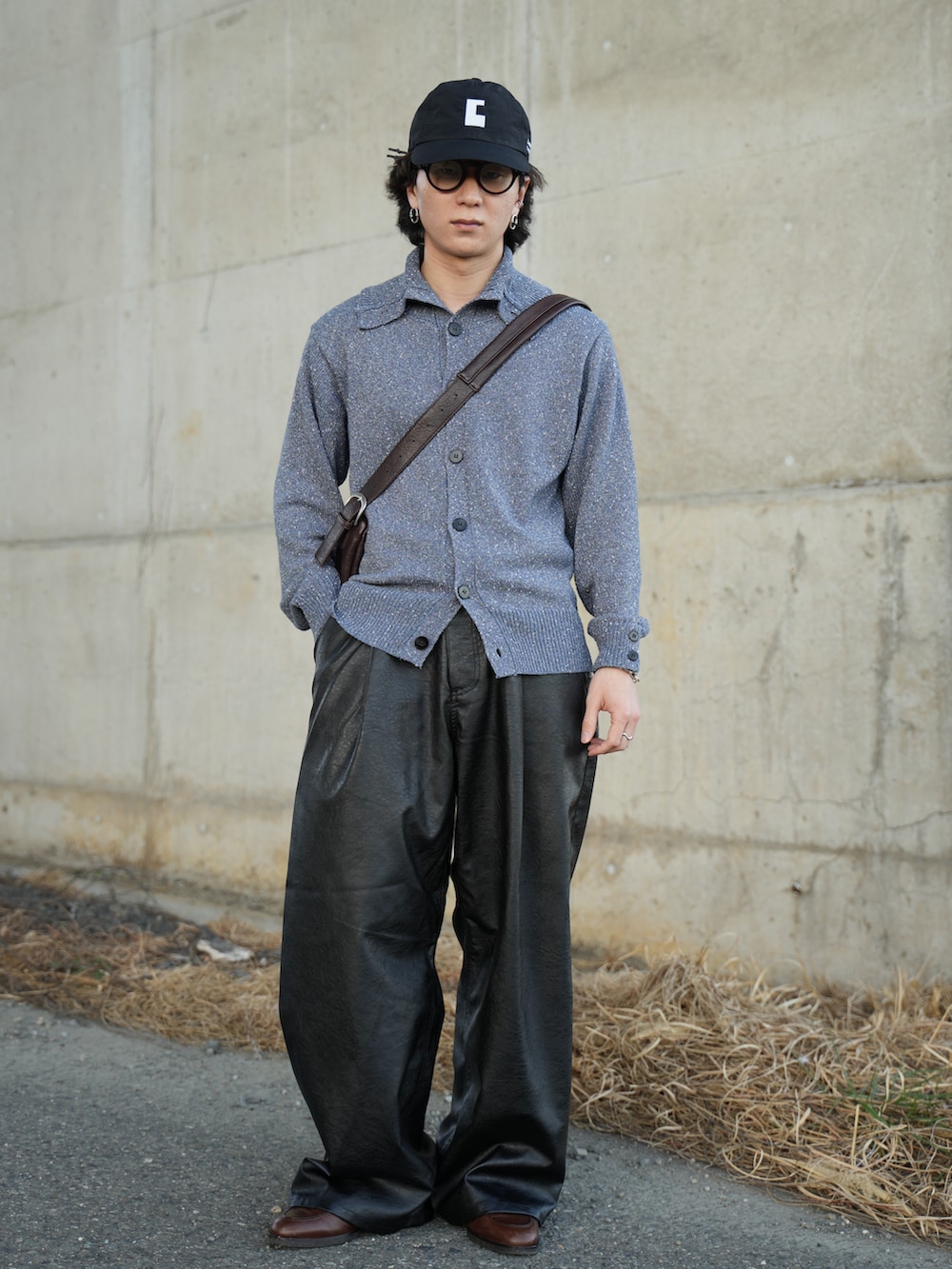 ブルー系のニット/セーター、ブラック系のスラックス、ブラウン系のショルダーバッグを着用したメンズの春コーディネートの3枚目の写真