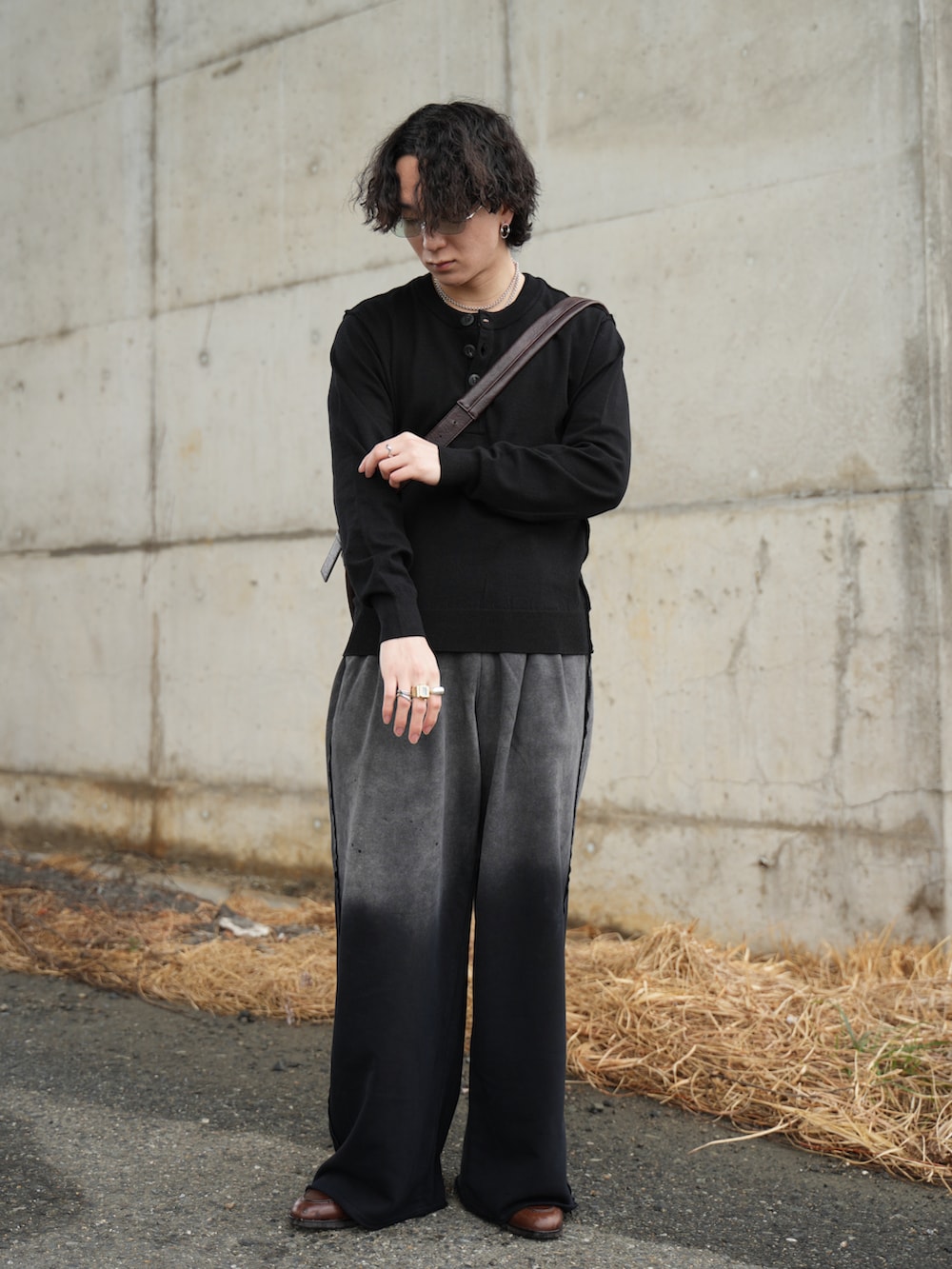 ブラック系のニット/セーター、ブラック系のスウェットパンツ、ブラウン系のショルダーバッグを着用したメンズの春コーディネートの4枚目の写真