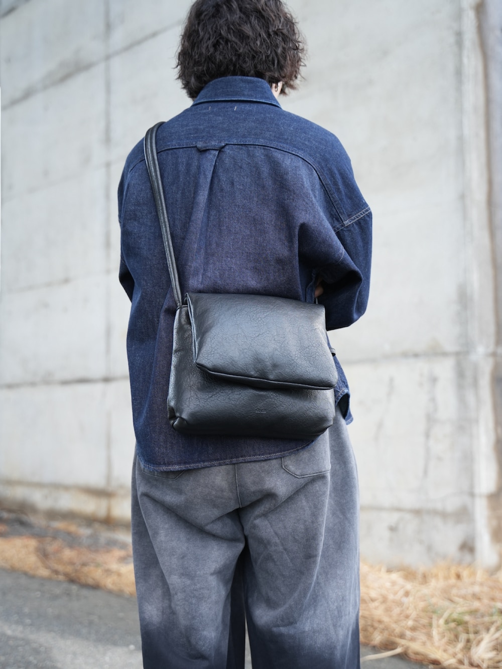 ブラック系のスウェットパンツ、ブラック系のショルダーバッグ、ブラック系のモカシン/デッキシューズを着用したメンズの冬コーディネートの4枚目の写真