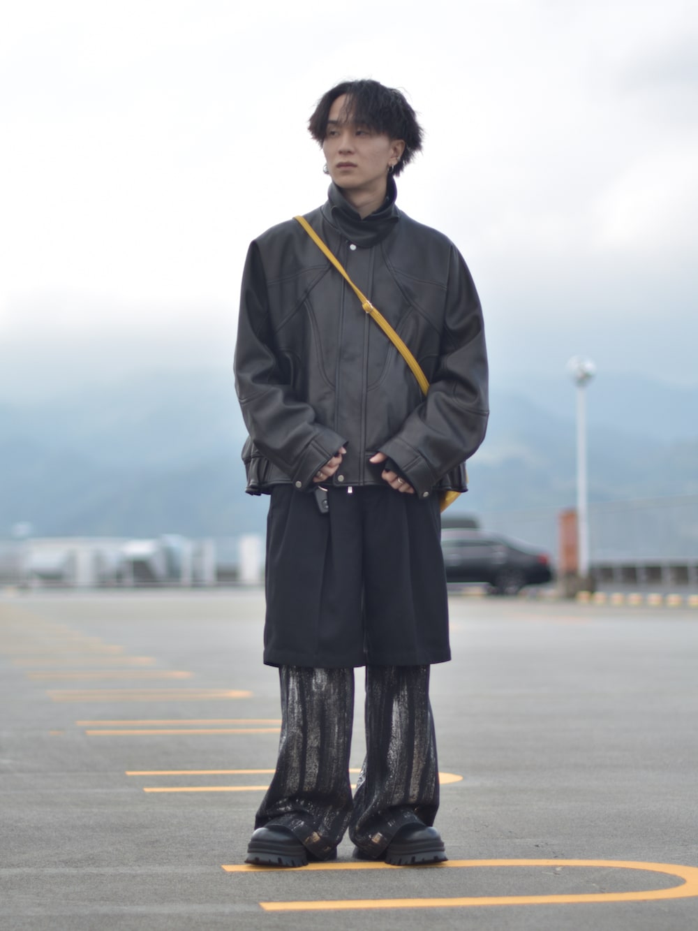 ブラック系のライダースジャケット、イエロー系のショルダーバッグ、ブラック系のその他パンツを着用したメンズの冬コーディネートの3枚目の写真