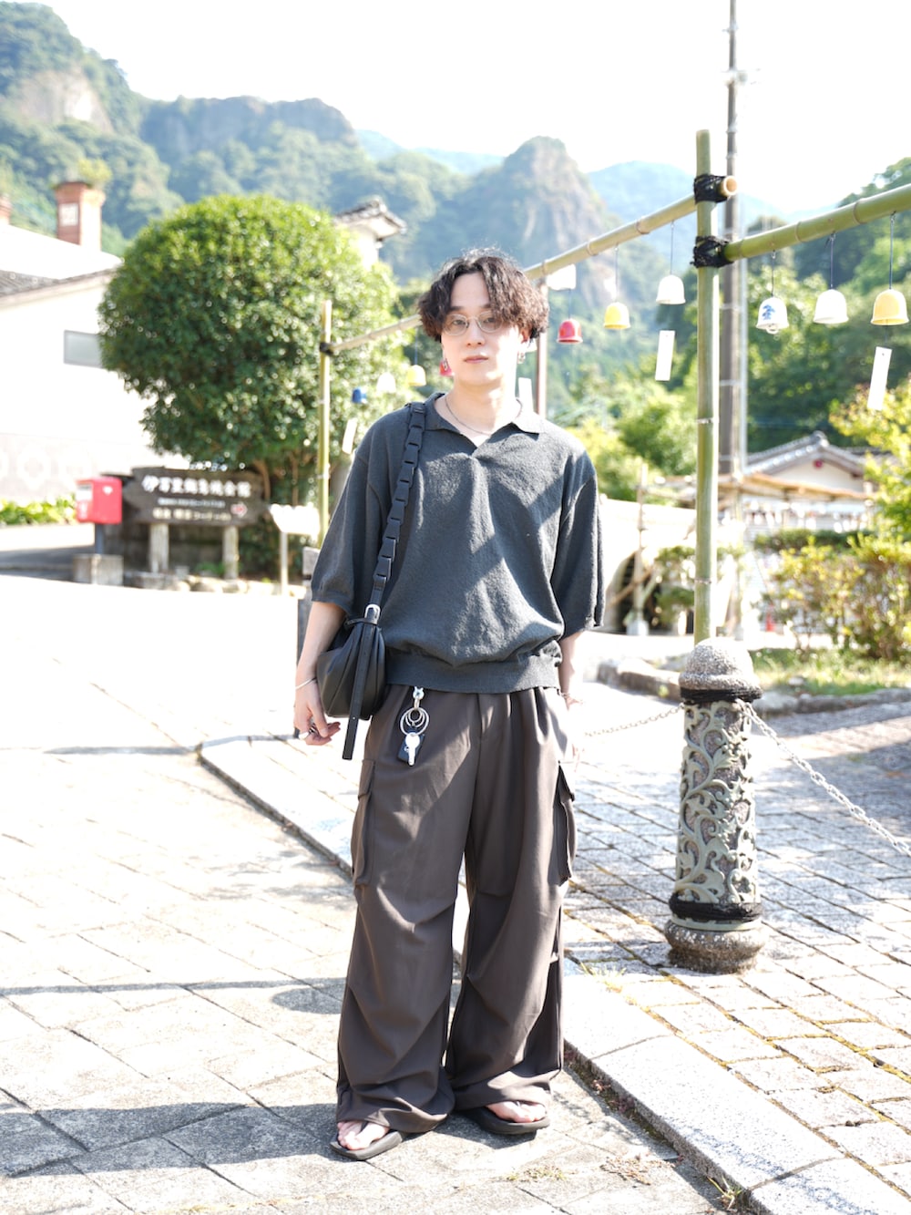 グレー系のポロシャツ、グレー系のその他パンツ、ブラック系のショルダーバッグを着用したメンズの夏コーディネートの4枚目の写真