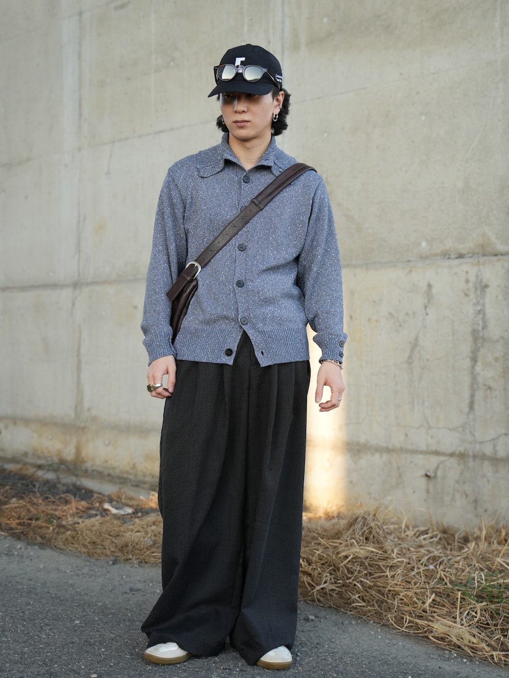 ブルー系のニット/セーター、ブラック系のスラックス、ホワイト系のスニーカーを着用したメンズの春コーディネートの5枚目の写真