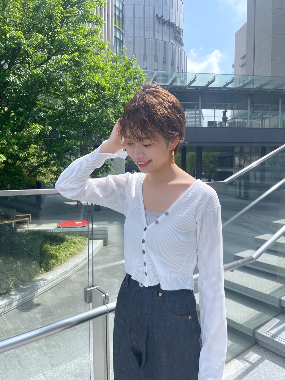 ブルー系のデニムパンツ、ホワイト系のカーディガン/ボレロ、ベージュ系のサンダルを着用したレディースの春コーディネートの4枚目の写真
