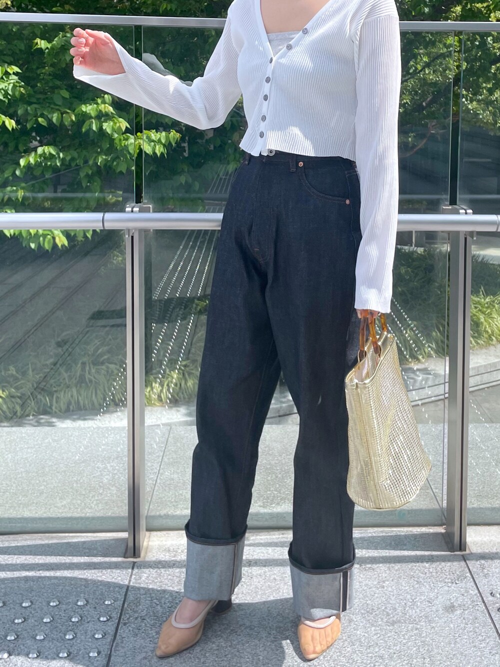 ブルー系のデニムパンツ、ホワイト系のカーディガン/ボレロ、ベージュ系のサンダルを着用したレディースの春コーディネートの3枚目の写真