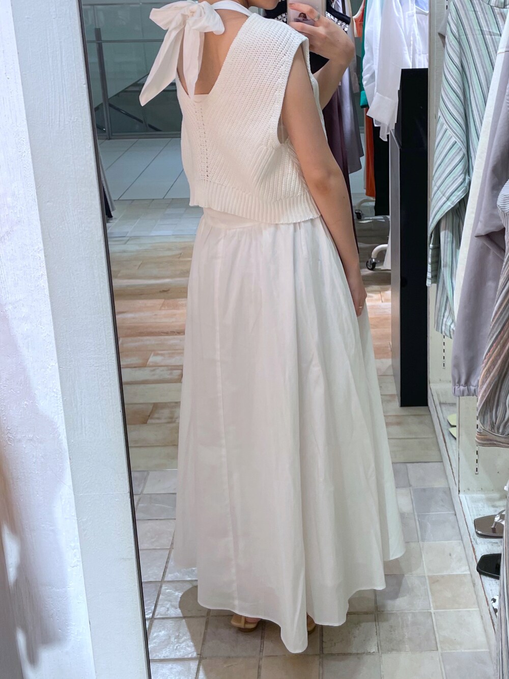 ブラック系のトートバッグ、ホワイト系のワンピースを着用したレディースの夏コーディネートの2枚目の写真