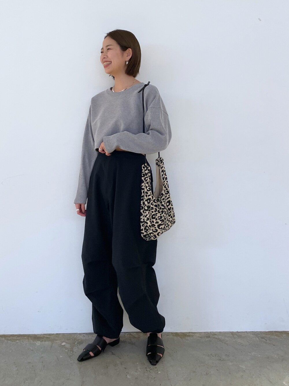 ブラック系のパンツ、ブラック系のワンピース、ブラック系のサンダルを着用したレディースの春コーディネートの2枚目の写真