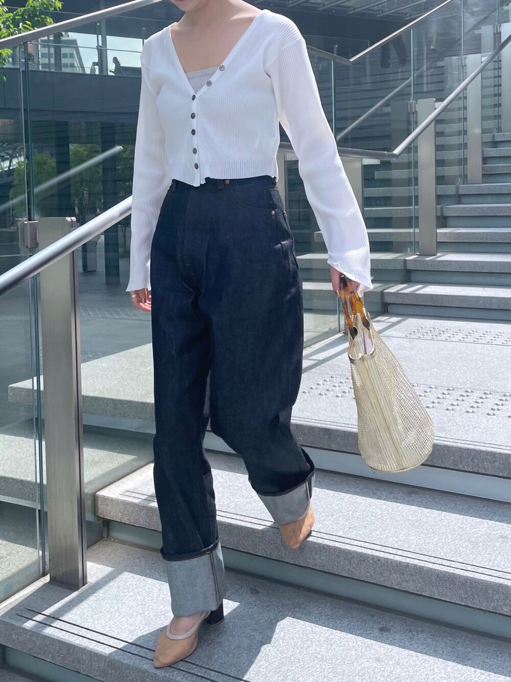 ブルー系のデニムパンツ、ホワイト系のカーディガン/ボレロ、ベージュ系のサンダルを着用したレディースの春コーディネートの2枚目の写真