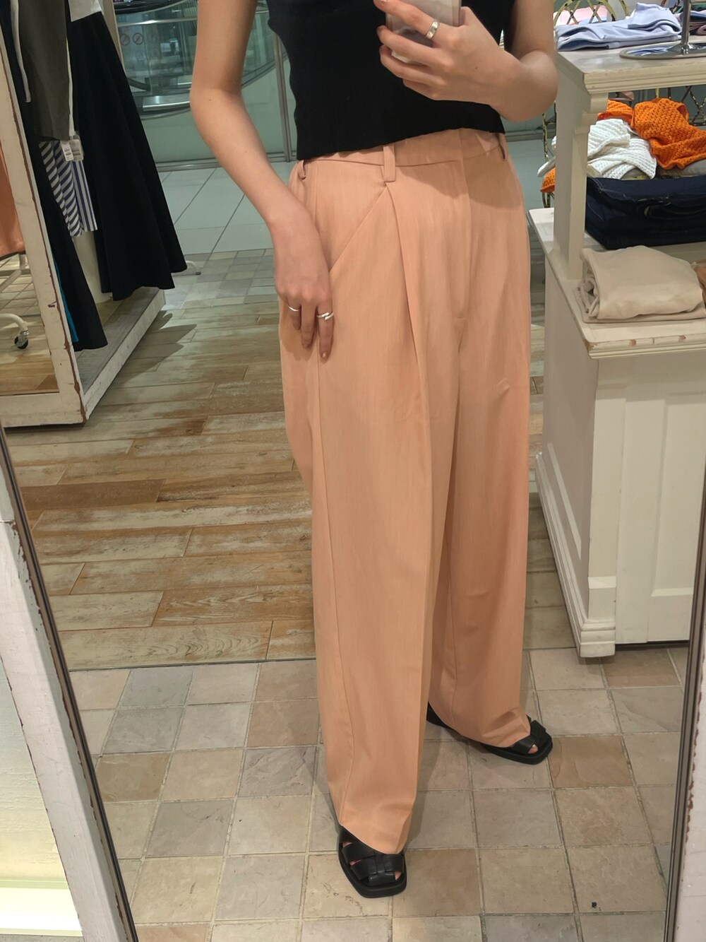 オレンジ系のスラックス、ブラック系のニット/セーター、ブラック系のスリッポンを着用したレディースの夏コーディネートの2枚目の写真