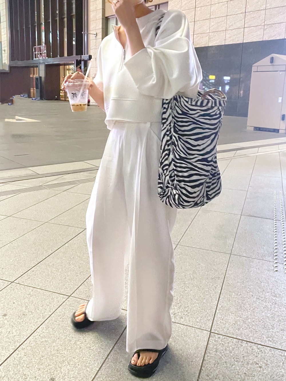 ホワイト系のTシャツ/カットソー、ブラック系のサンダル、ホワイト系のスラックスを着用したレディースの春コーディネートの2枚目の写真